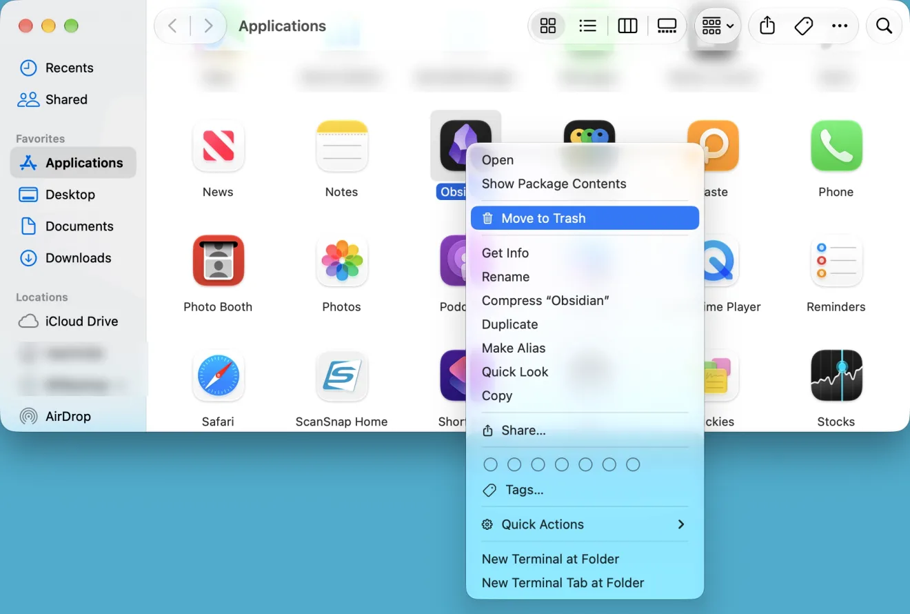 The Applications folder in a Finder window, shown as icons. The app Obsidian is selected and Control-clicked. In the menu that appeared, below Open and Show Package Contents, the item Move to Trash is highlighted in blue