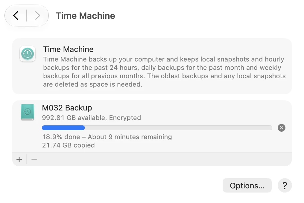 The Time Machine screen. The disk M032 Backup shows 992.81 GB available, Encrypted, and a progress bar with 18.9% done – About 9 minutes remaining. Below the disk are the + and − buttons, and an Options button is in the bottom right